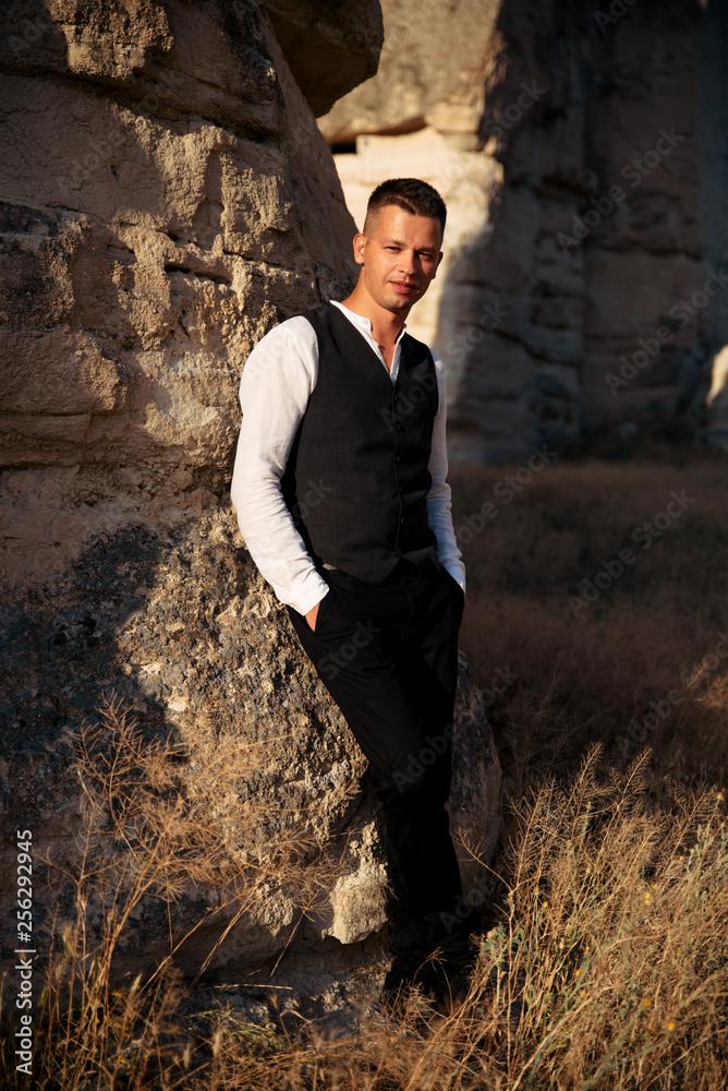 Handsome guy standing near a rock Handsome guy standing near a rock