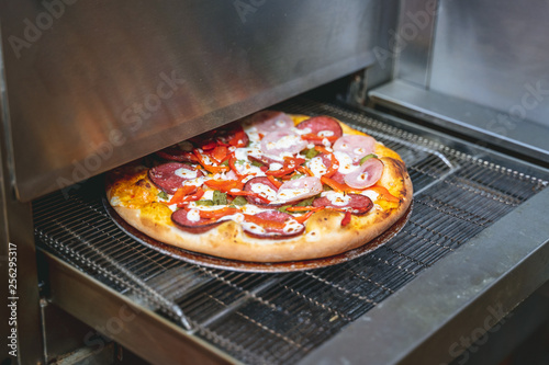 Fresh cooked pizza modern industrial oven in a restaurant 