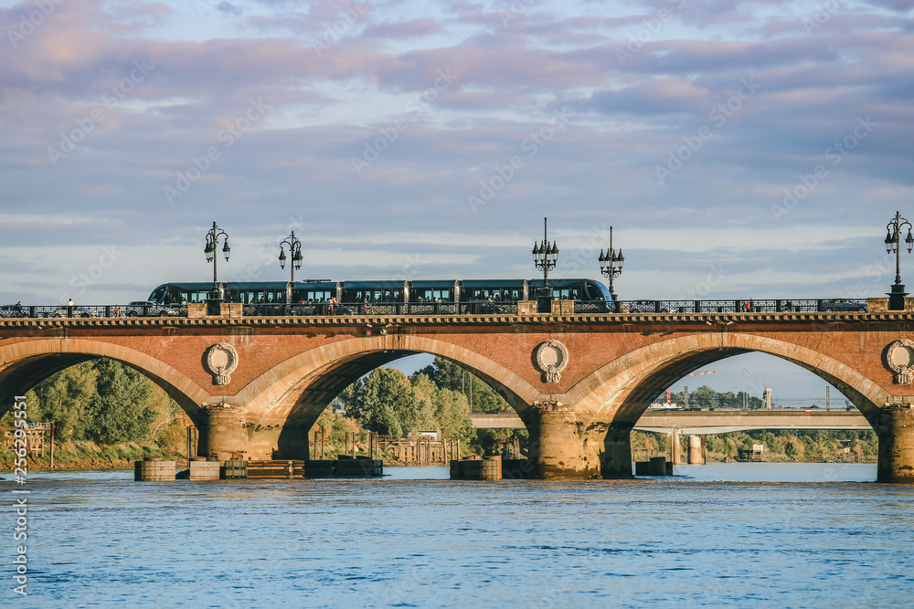 View of Tram is crossing Pont de Pierre bridge or Pont de Pierre in the morning from Garonne river, Bordeaux, France