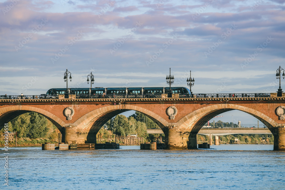 Obraz premium View of Tram is crossing Pont de Pierre bridge or Pont de Pierre in the morning from Garonne river, Bordeaux, France