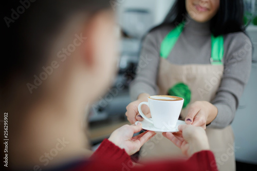 Barista in apron in coffee shop give just brewed fresh coffee to customer