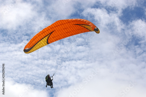 Tandem paraglider flying orange wing