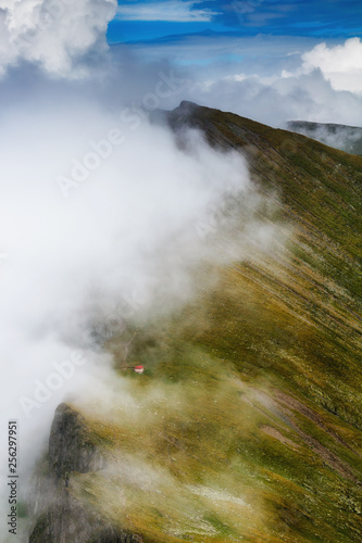 Amazing landscape of summer mountains. View of fog and low clouds over Fagaras Mountains are the highest mountains of the Southern Carpathians. Transylvania. Romania. Travel background. 