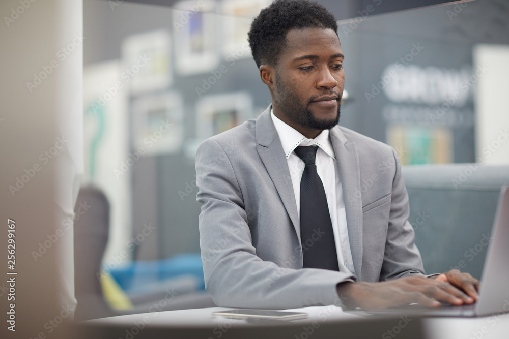 Portrait of handsome African businessman using laptop while working in office, copy space Portrait of handsome African businessman using laptop while working in office, copy space