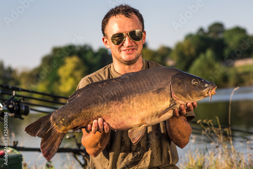 Happy angler with carp fishing trophy
