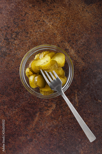 Pickled gherkins with mustard and garlic on a stone rusty background.