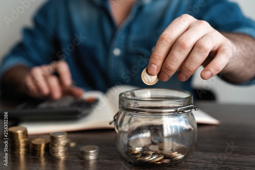 business accounting with saving money with hand putting coins in jug glass concept financial.