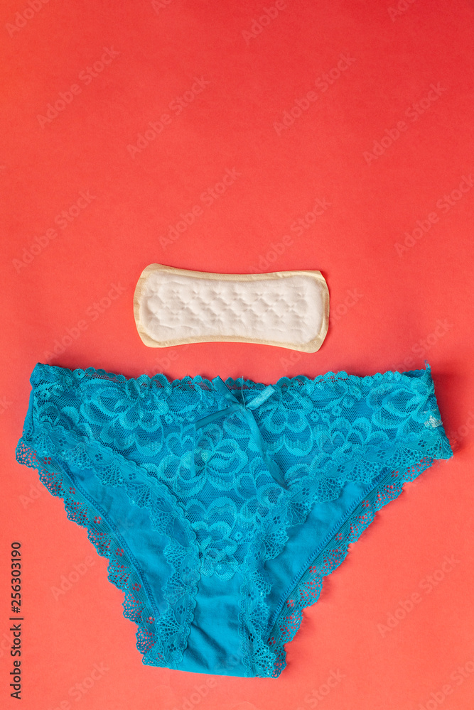 Women's underwear and sanitary pad. Feminine sanitary napkin and blue sexy  women's lace panties on red background Stock Photo | Adobe Stock