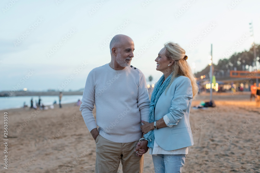Spain, Barcelona, happy senior couple on the beach at dusk Spain, Barcelona, happy senior couple on the beach at dusk