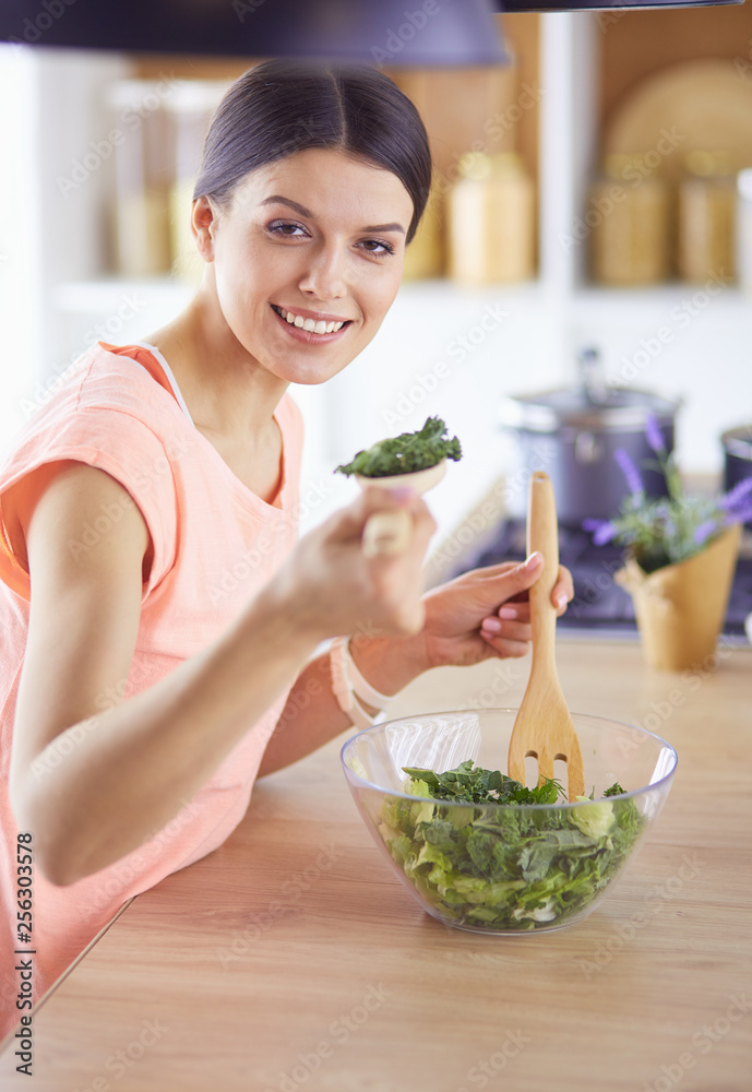 Smiling young woman mixing fresh salad in the kitchen. Smiling young woman mixing fresh salad in the kitchen.