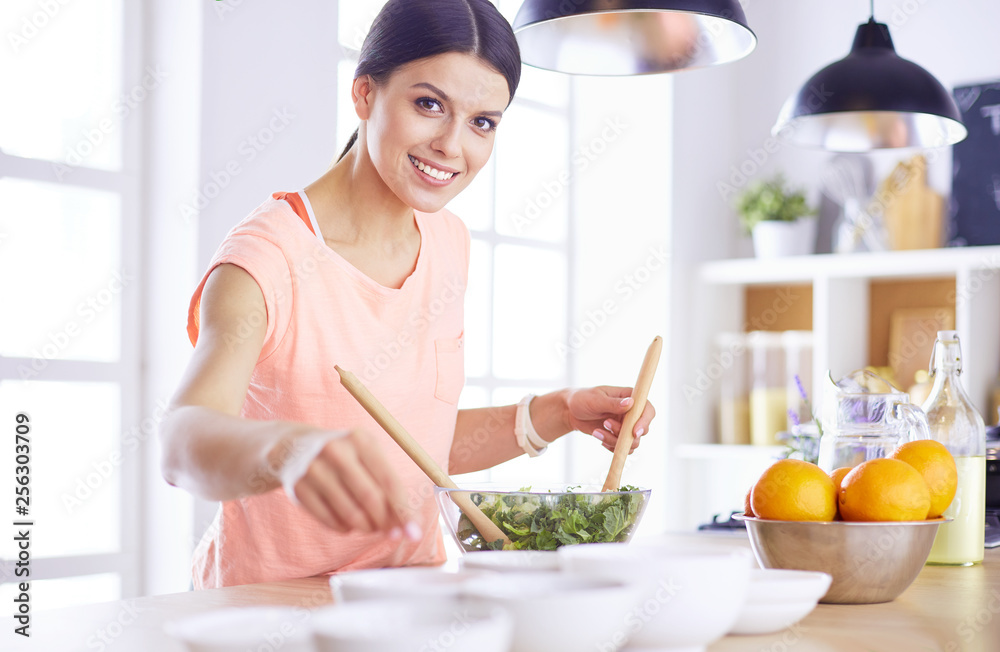 Smiling young woman mixing fresh salad in the kitchen. Smiling young woman mixing fresh salad in the kitchen.