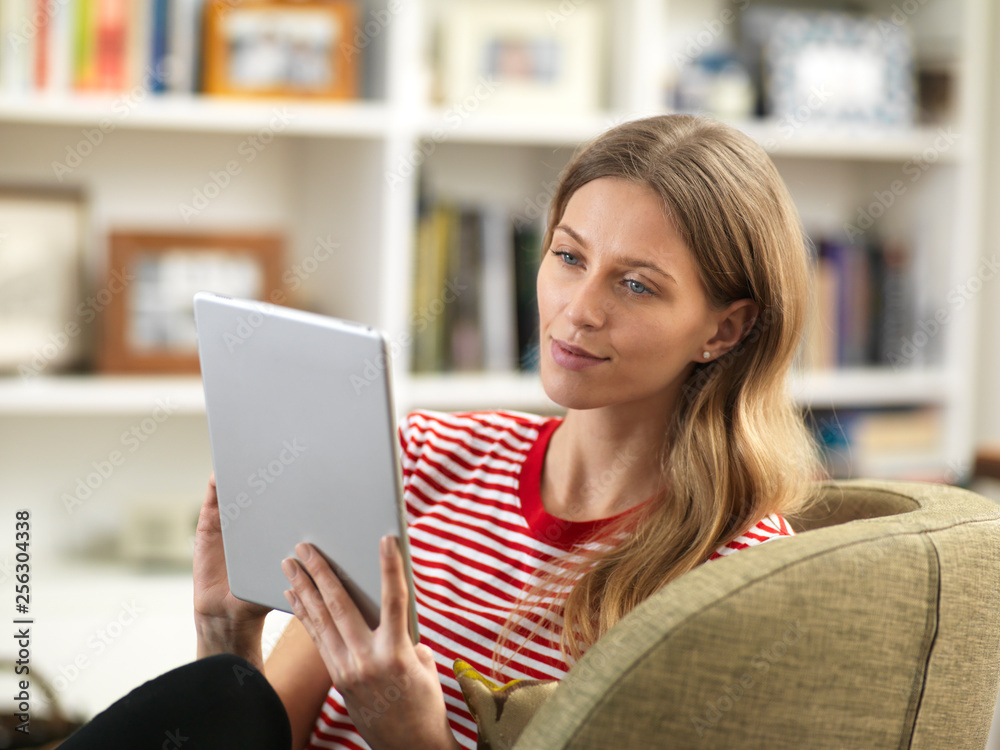 Young woman relaxing at home using a tablet Young woman relaxing at home using a tablet