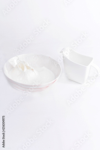 Milk splashed on a large bowl and saucer on white background, isolated
