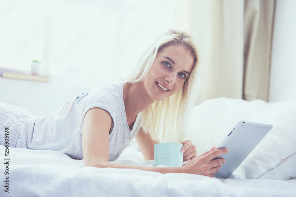 Girl holding digital tablet with blank screen and smiling at camera in bedroom Girl holding digital tablet with blank screen and smiling at camera in bedroom