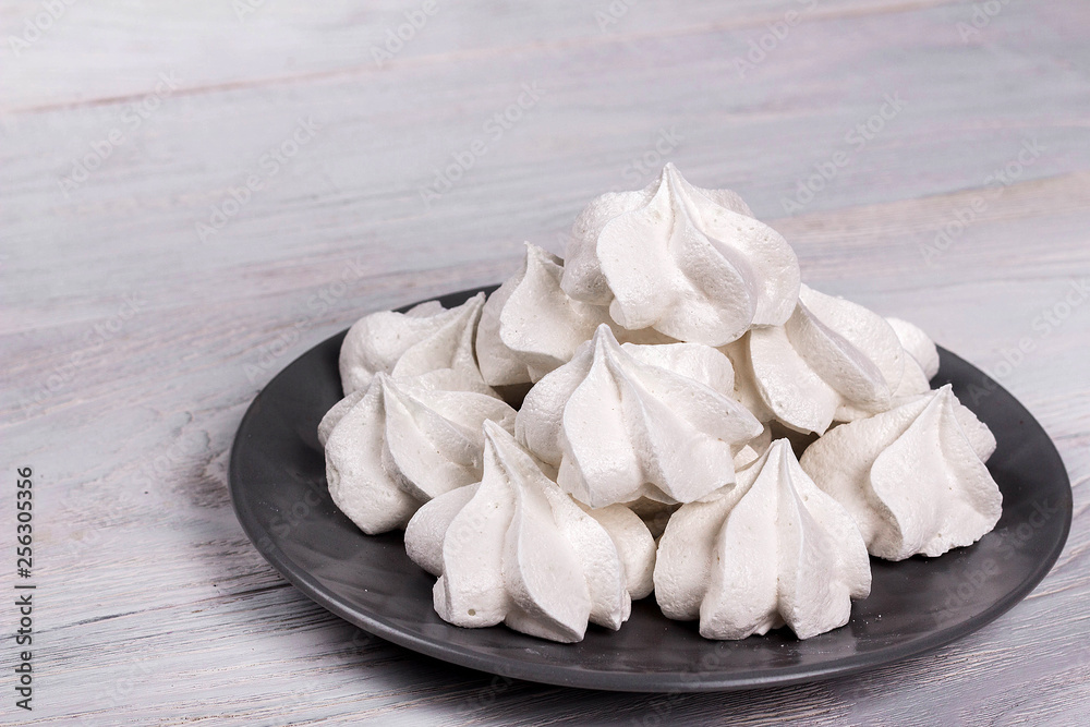 merengues on gray plate on white wooden background