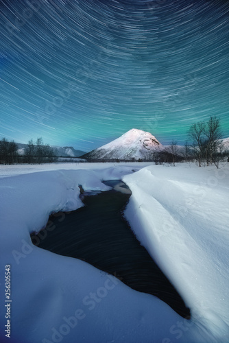 frozen lake in the mountains with startrails 