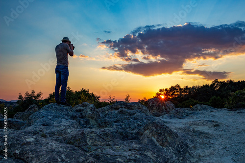 Rear view of unrecognizable male photographer taking pictures of the sunset over the Stone Mushrooms near Beli Plast village, Kardzhali Municipality, Bulgaria