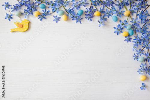Easter background with blue flowers and candy eggs