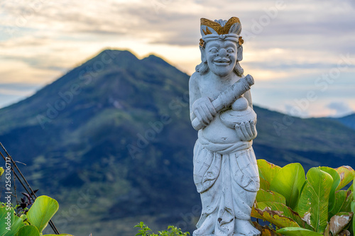 Traditional Balinese sculpture against the background of the volcano Batur on sunrise, morning time. Island Bali, Indonesia. Closeup