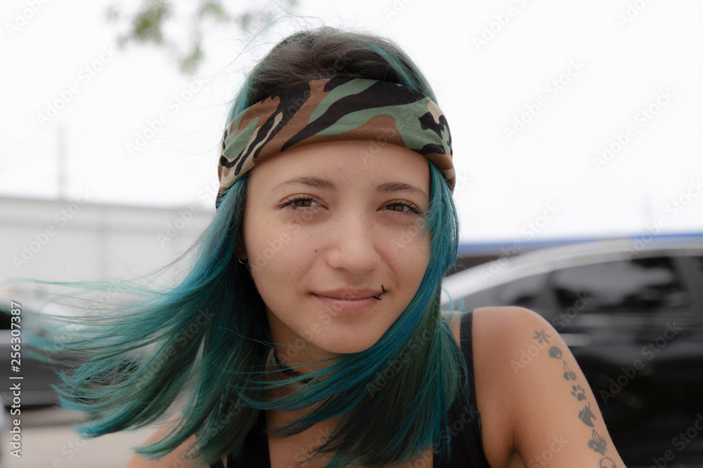 Portrait of a cute young hipster girl with blue hair. a bandana is tied on  the head.The girl has beautiful hair in the wind. 70's retro style. Stock  Photo