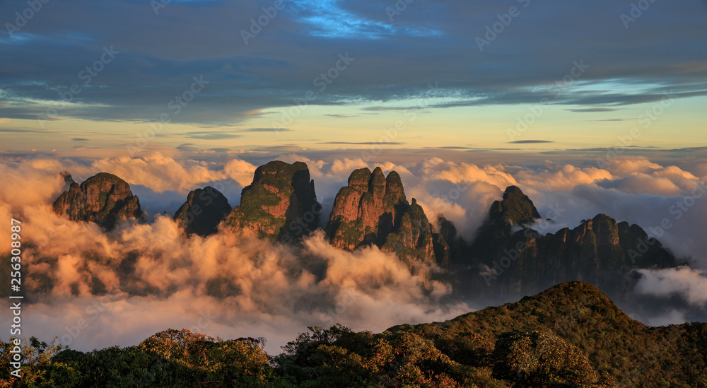 Chinese Karst Mountains above the clouds, steep cliffs covered in exotic trees. Dayao Mountain range near Jinxiu City, Guangxi Province China. Shengtang Mountain, Shengtangshan. Sunset, Sea of Clouds