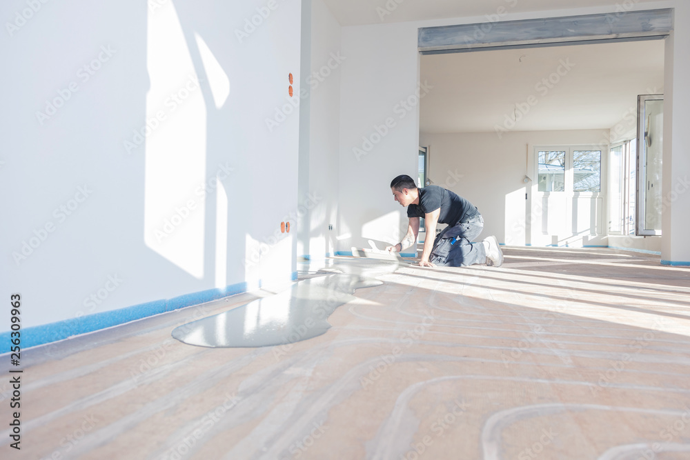 Plasterer during floor covering works with self-levelling cement mortar Plasterer during floor covering works with self-levelling cement mortar
