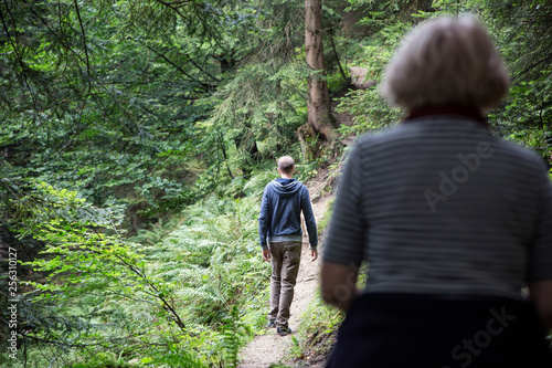 Austria, Tyrol, Kaiser mountains, mother and adult son hiking in forest photo