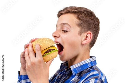 Caucasian boy eating burger and hamburger on white background, bun.