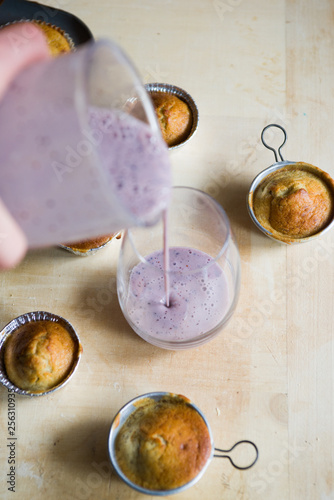 Pouring Blueberry smoothies with lactose free almond milkbanana muffins, concept for healthy breakfast and snack. photo