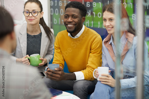 Multi-ethnic group of business people dressed in casual wear chatting in break room