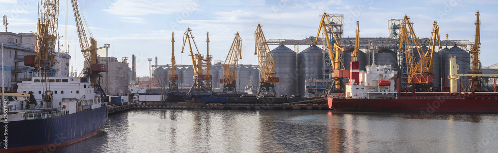 Loading grain to the ship in the port. Panoramic view of the ship, cranes, and other infrastructures of the port.