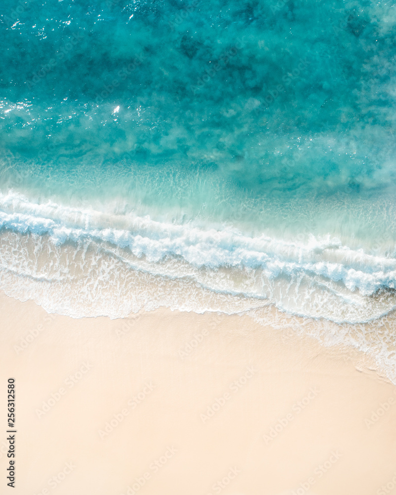 Beautiful aerial shot of a beach with nice sand, blue turquoise water. Top shot of a beach scene with a drone