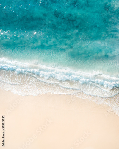 Beautiful aerial shot of a beach with nice sand, blue turquoise water. Top shot of a beach scene with a drone photo