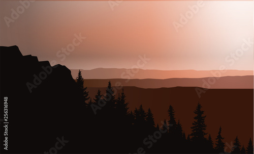 Panorama of mountains. Sunset. Silhouette of rocks and coniferous trees on the background of colorful sky.
