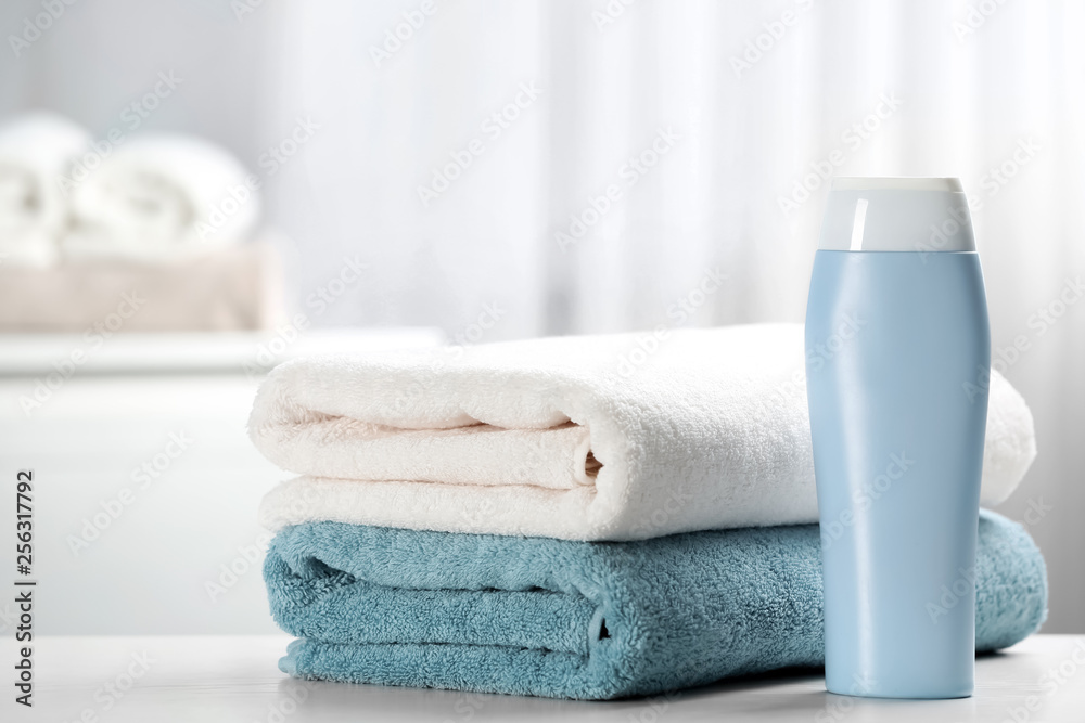 Clean towels and shampoo bottle on table. Space for text Clean towels and shampoo bottle on table. Space for text