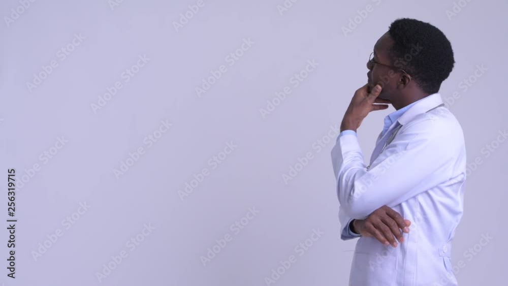 Profile view of young happy African man doctor thinking Profile view of young happy African man doctor thinking
