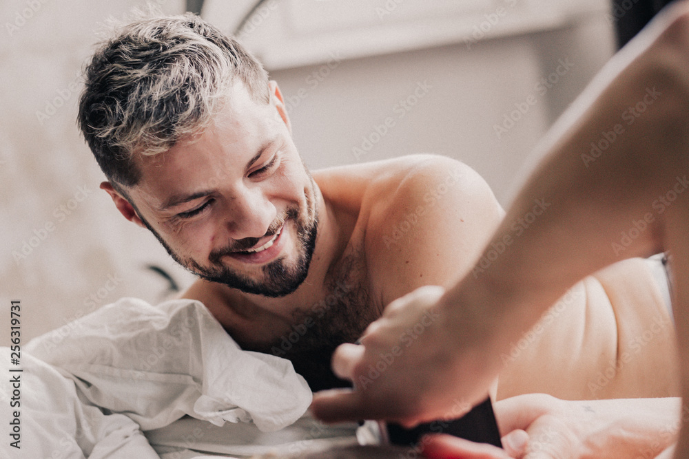 Portrait of smiling gay man with his partner in bed