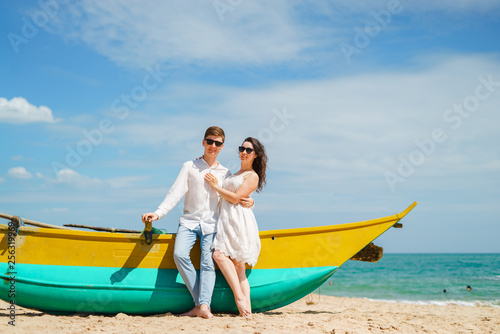 Couple in love of happy man and woman, travel. Beach wooden boat sand