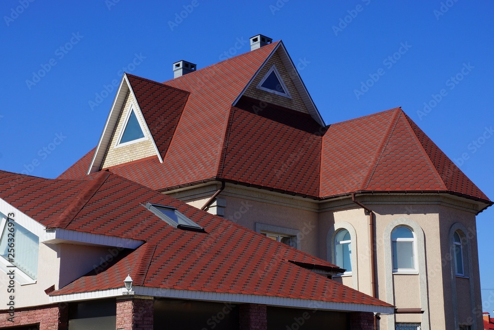 red tile on the roof of the attic of a large house with a window against the blue sky
