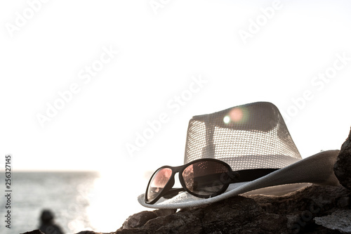 Close up straw hat and sunglasses  on stone at sunnset background. Summer vacation concept. traveling and relax. photo