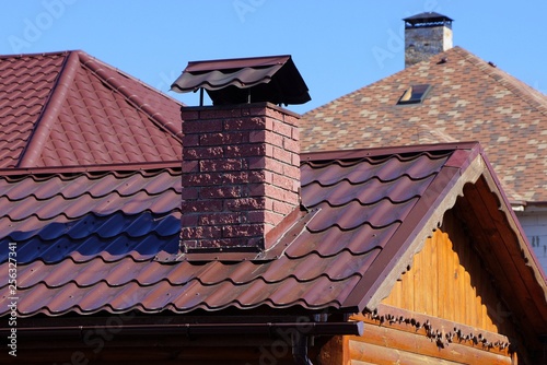 part of the roof with red tiles and brick chimney