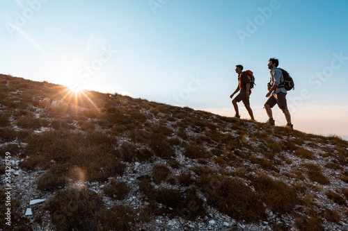 Italy, Monte Nerone, two men hiking in mountains at sunset