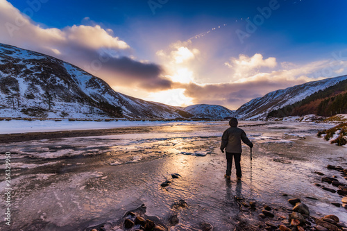 United Kingdom, Scotland, Highlands, female hiker standing at icy riverside
