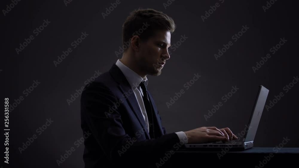 Serious manager in suit working on laptop until late night, career promotion Serious manager in suit working on laptop until late night, career promotion