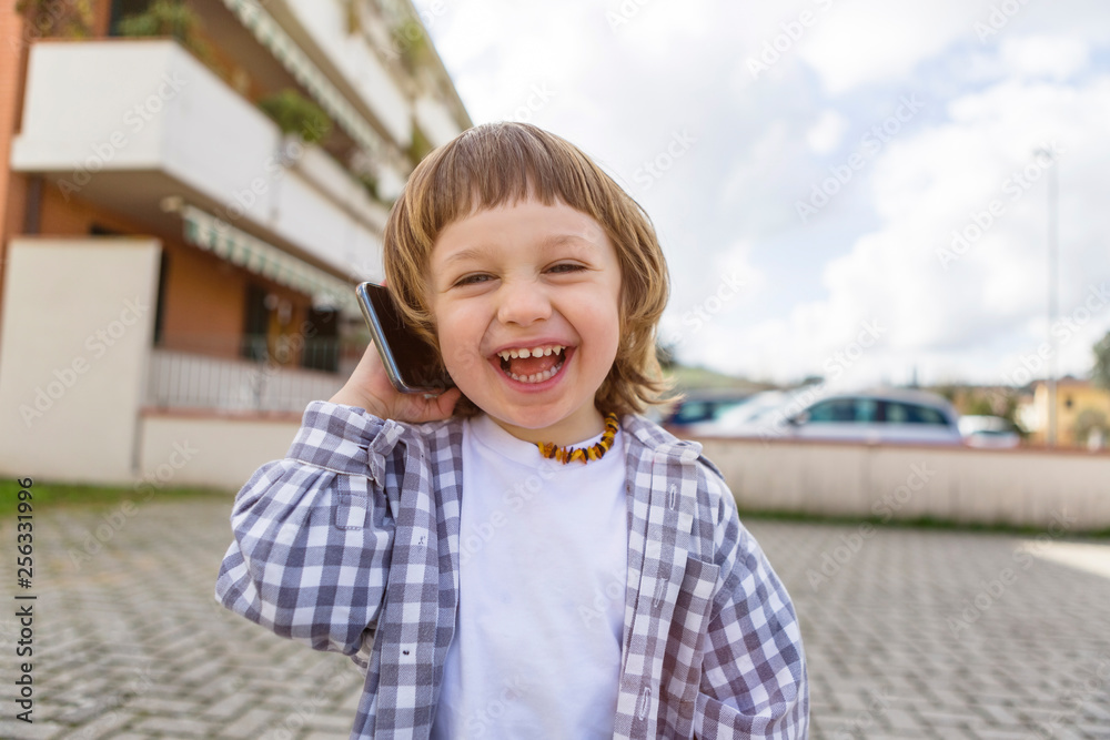 Portrait of laughing toddler boy on cell phone outdoors Portrait of laughing toddler boy on cell phone outdoors