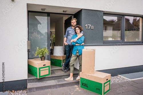 Couple standing at house entrance with cardboard boxes