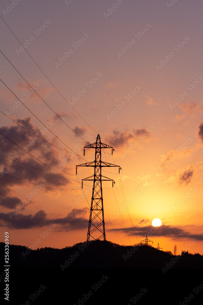 沈む太陽と送電線の鉄塔　夕焼け　空　美しい風景