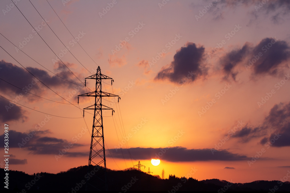 沈む太陽と送電線の鉄塔　夕焼け　空　美しい風景