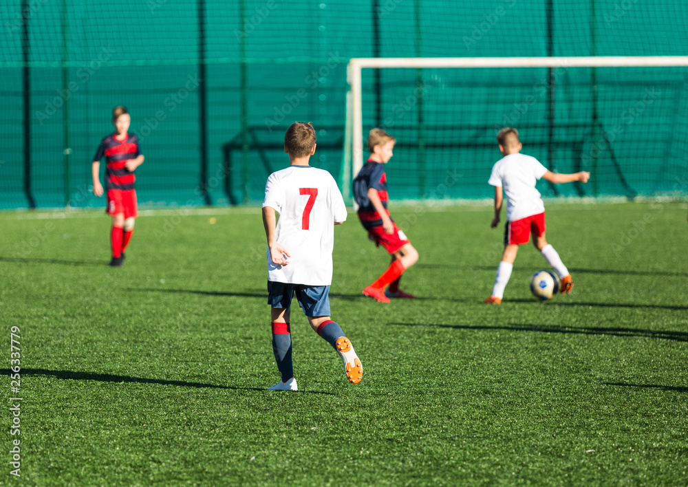 Obraz premium Football training soccer for kids. Boy runs kicks dribbles soccer balls. Young footballers dribble and kick football ball in game. Training, active lifestyle, sport, children activity concept