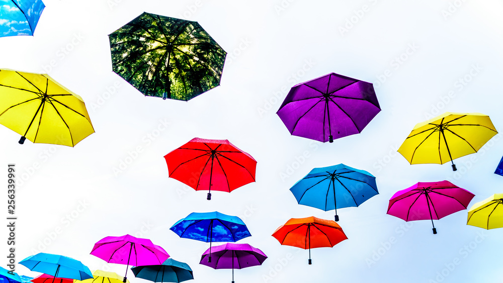 Colorful Umbrellas floating in the air under cloudy sky